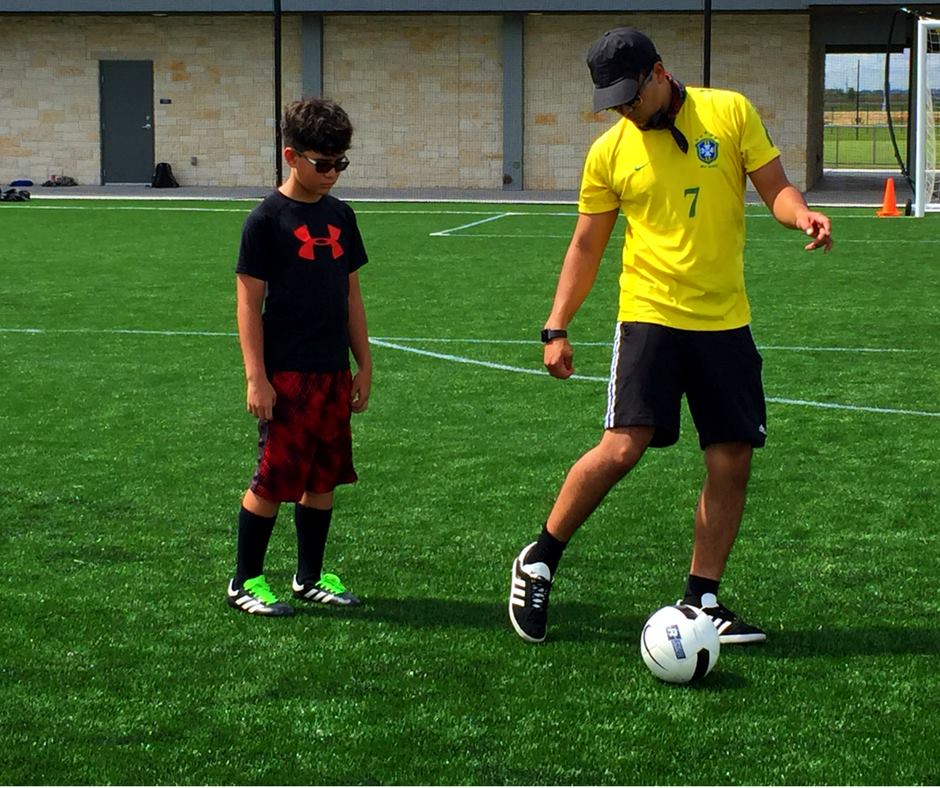 Coach and Soccer player kicking ball